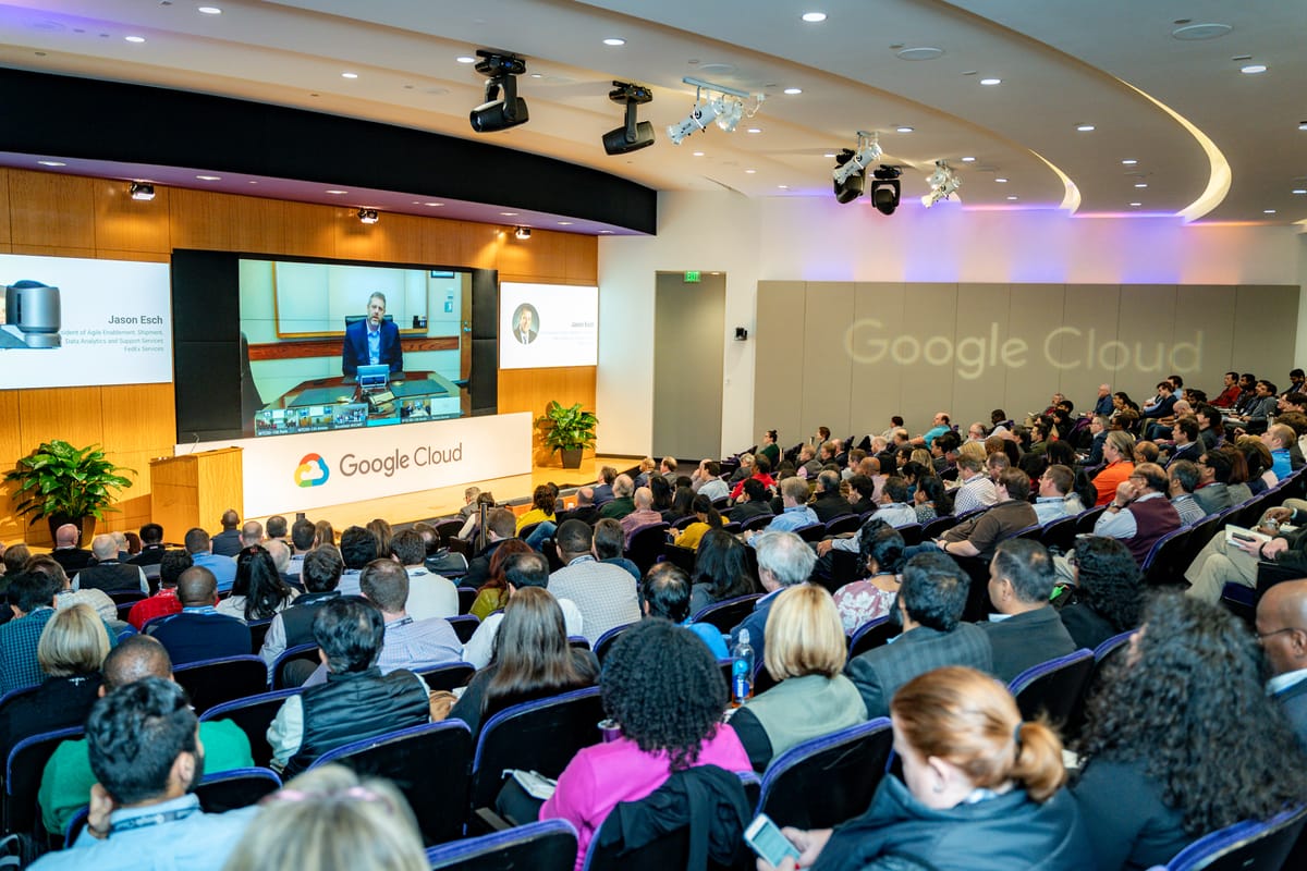 Full Google Cloud auditorium watching a remote speaker on the main presentation screen