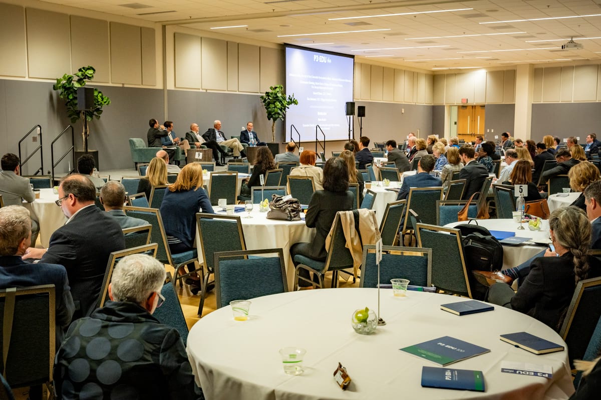 P3EDU panel speaking to attendees seated at round tables in a conference room
