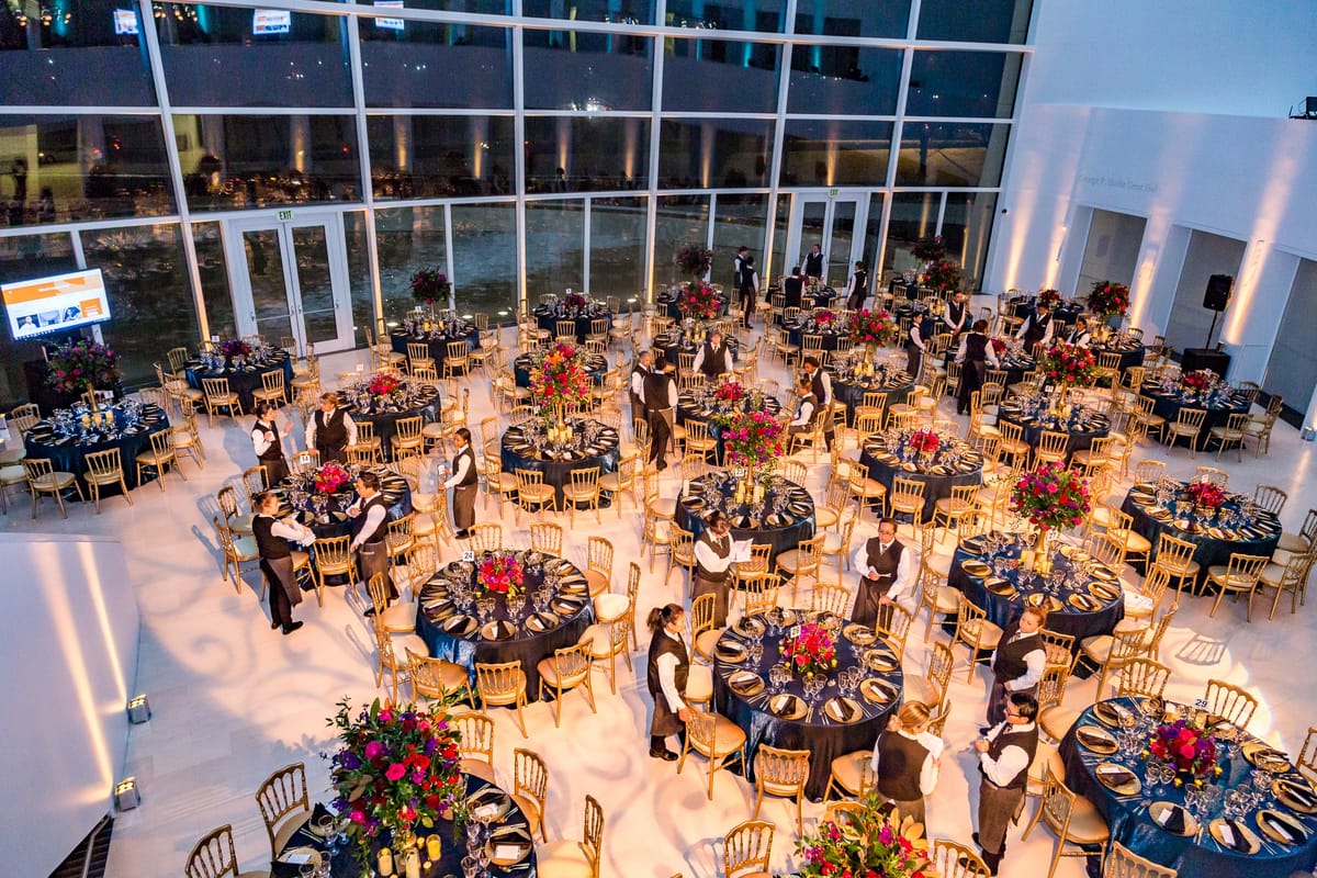 Overhead view of a formal corporate gala with guests seated throughout a bright museum atrium