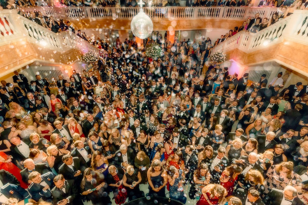 Formal gala filling the National Women's History Museum beneath a mirrored ball and falling confetti