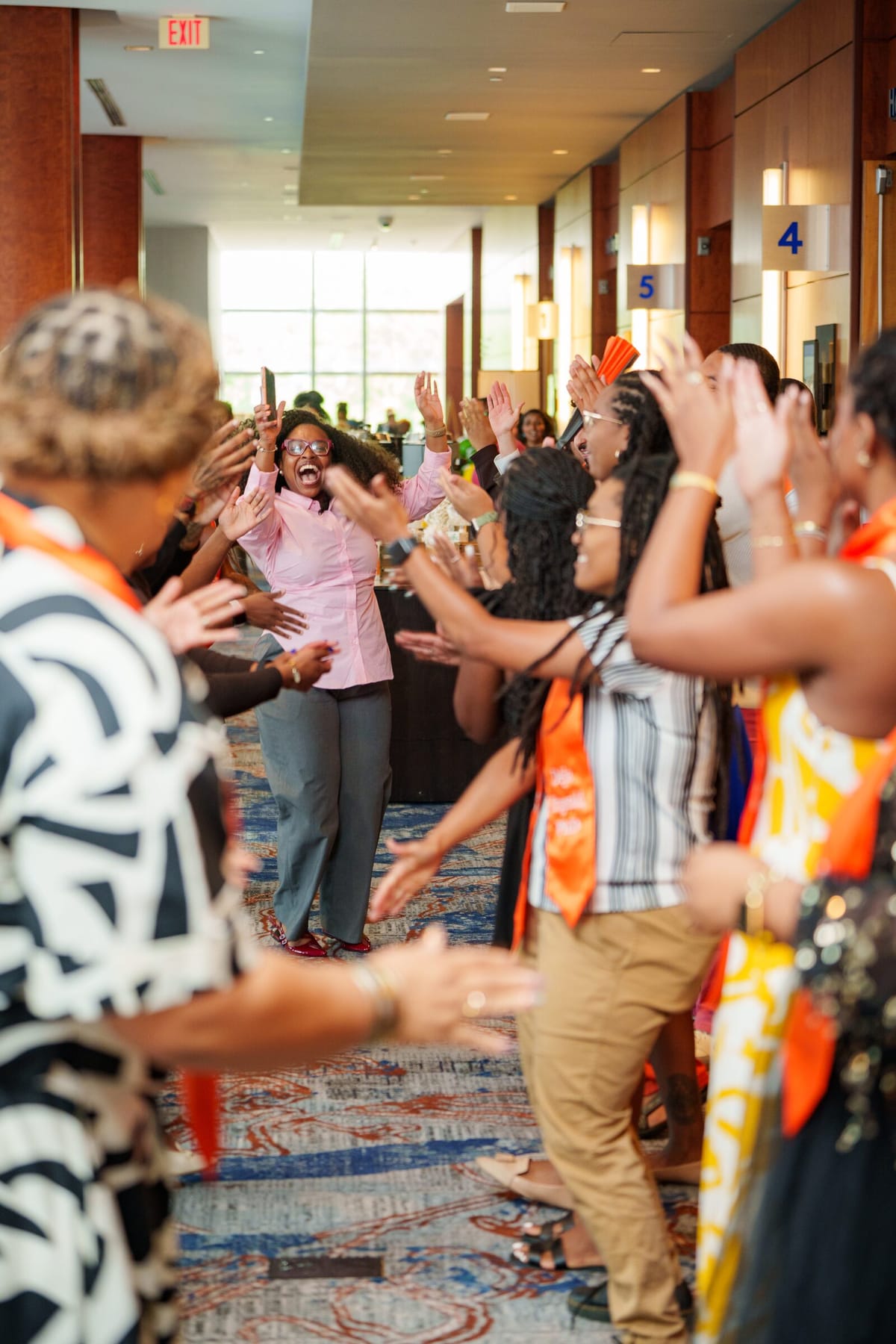 Scholars celebrating a colleague walking through a cheering line in a hotel corridor