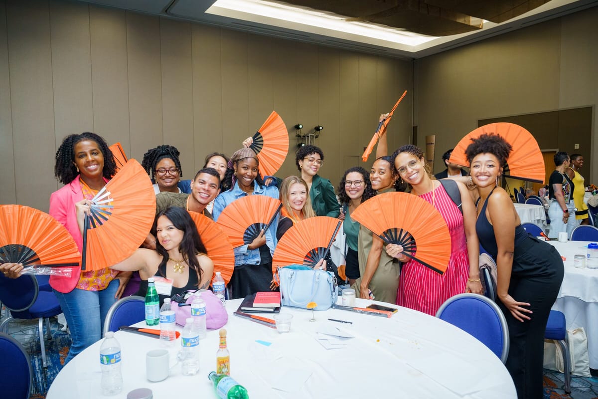 Scholars celebrating with orange fans at round tables during the completion ceremony