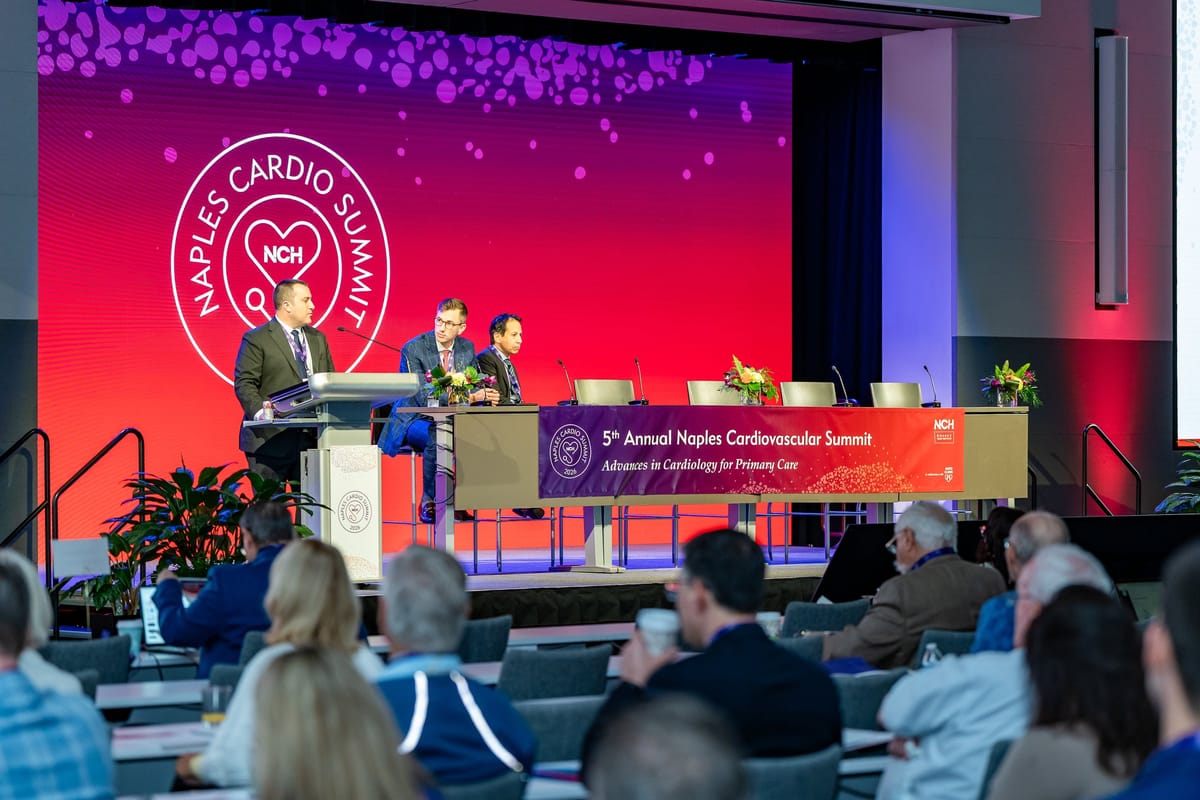 Clinical panel discussion photographed with the branded summit stage and audience